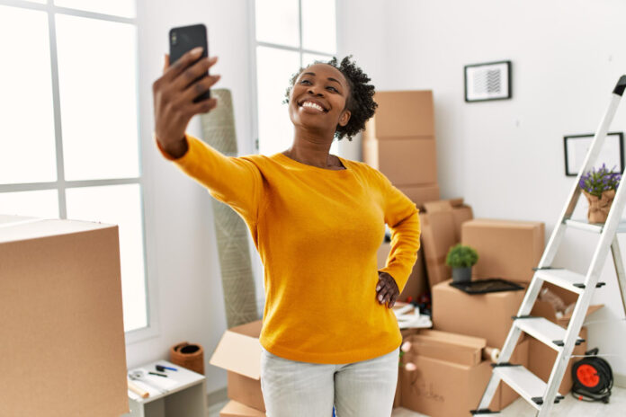 woman taking selfie with cardboard boxes in new home